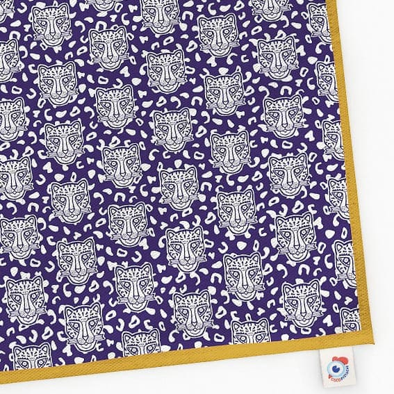Torchon Grrrminet bleu bord ocre Famille GRRR. Fond bleu foncé, motif rosette et têtes de léopard.