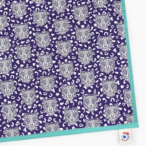 Torchon Grrrminet bleu bord turquoise Famille GRRR. Fond bleu foncé, motif rosette et têtes de léopard.